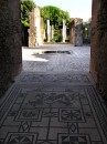 Mosaic entry and courtyard * A mosaic entryway into one of the houses in Pompeii.  Many featured an inner courtyard like this one. * 323 x 432 * (59KB)